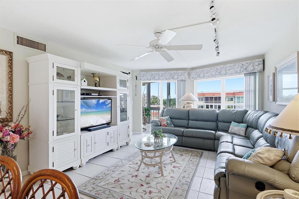 A hallway with tiled floors leads to a bathroom, flanked by framed artwork and decor — 1215 S PORTOFINO DRIVE UNIT 406, SARASOTA, FL