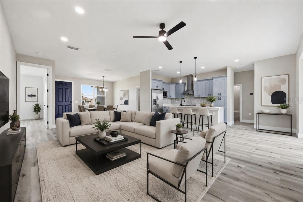 An open-concept living room and kitchen featuring light wood flooring and blue cabinetry — 367 CAMELLIA COURT, KISSIMMEE, FL