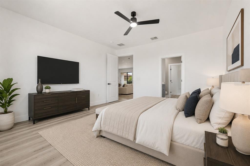 A modern bedroom features a bed, dark wood dresser, wall-mounted television, and light wood flooring — 367 CAMELLIA COURT, KISSIMMEE, FL