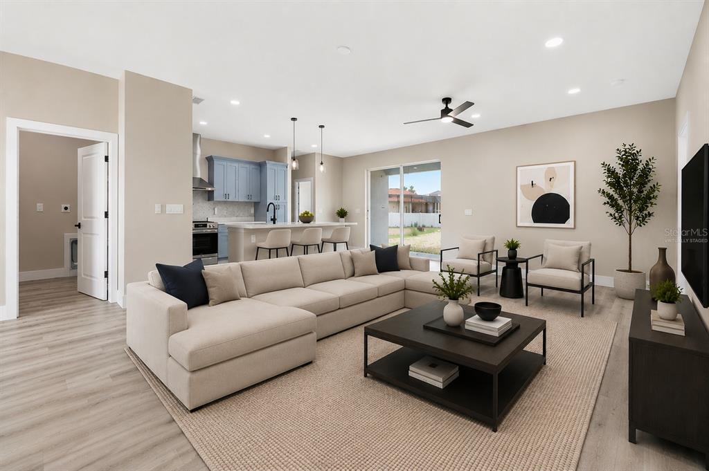 A living room with a sectional sofa, coffee table, and an open kitchen with blue cabinets — 367 CAMELLIA COURT, KISSIMMEE, FL