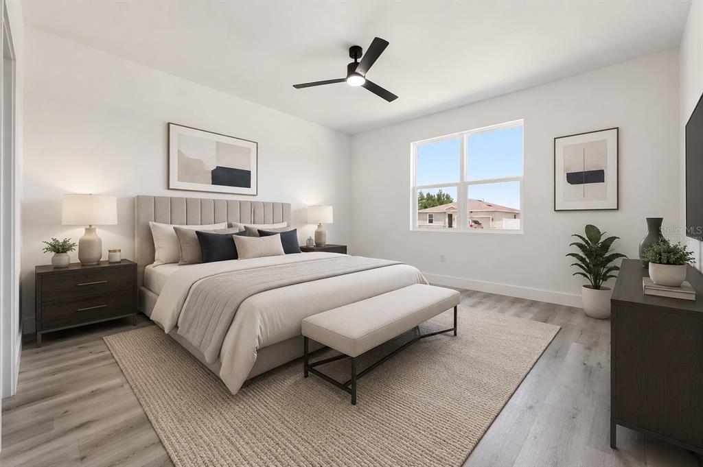 This bedroom features a king bed, a ceiling fan, and light wood-look flooring — 367 CAMELLIA COURT, KISSIMMEE, FL