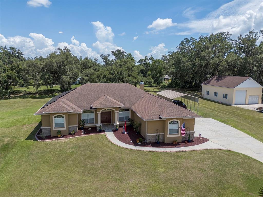 An aerial view shows a tan house with a brown roof, a detached garage, and landscaping — 3823 ANCIENT OAK TRAIL, PLANT CITY, FL
