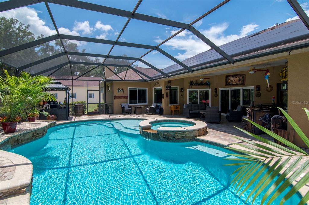 A screened-in patio features a swimming pool with an integrated hot tub and lounge furniture — 3823 ANCIENT OAK TRAIL, PLANT CITY, FL