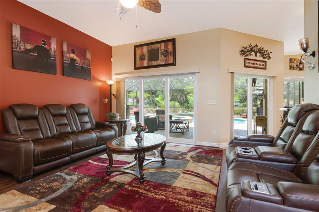 A living room with brown leather recliners, a patterned rug, and sliding doors to a pool — 3823 ANCIENT OAK TRAIL, PLANT CITY, FL