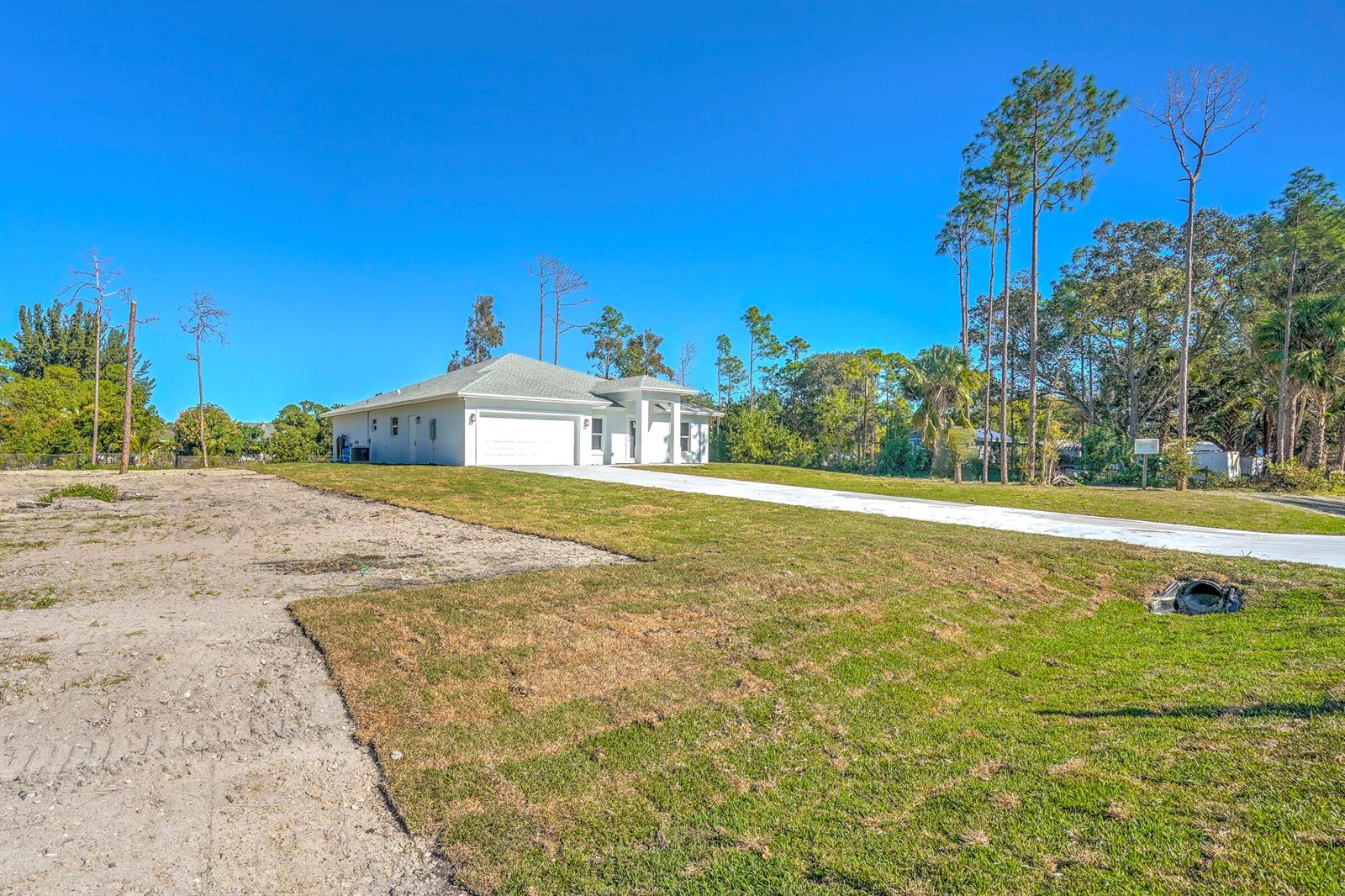 A single-story white house with a garage sits on a grassy lot under blue skies — 13875 63rd Lane N, FL 33470, FL