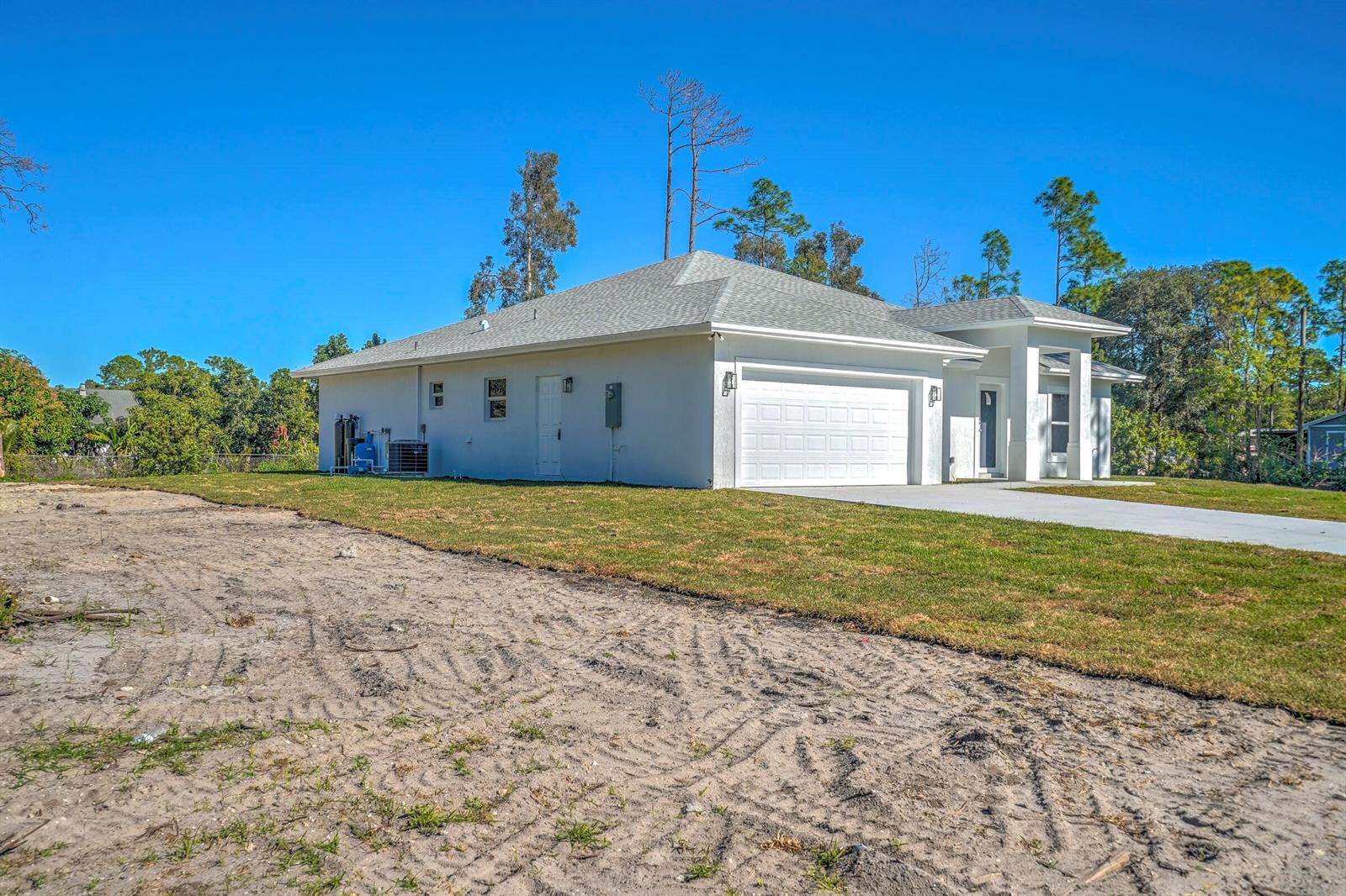 A side view of a white single-story house with a garage and a sandy yard — 13875 63rd Lane N, FL 33470, FL