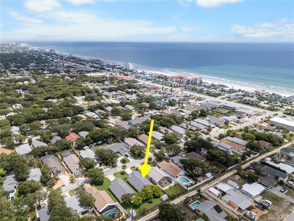 An aerial view shows a residential neighborhood near the coast with a yellow arrow pointing down — 815 E 23RD AVENUE, NEW SMYRNA BEACH, FL