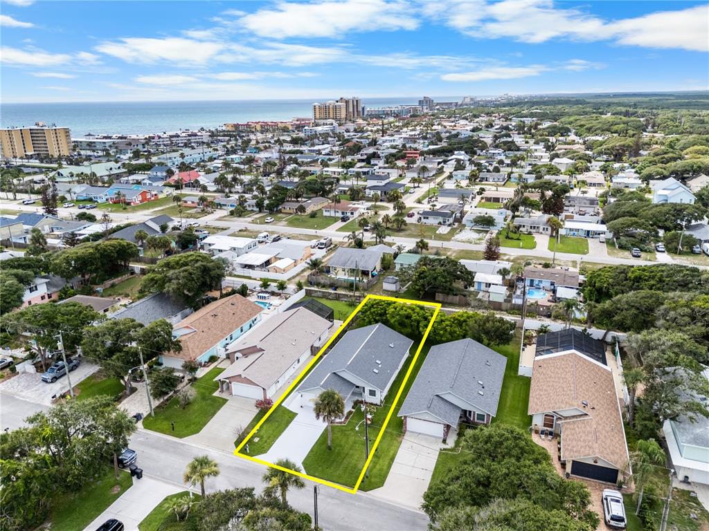 An aerial view shows a single-story house with a yellow outline on a residential lot — 815 E 23RD AVENUE, NEW SMYRNA BEACH, FL