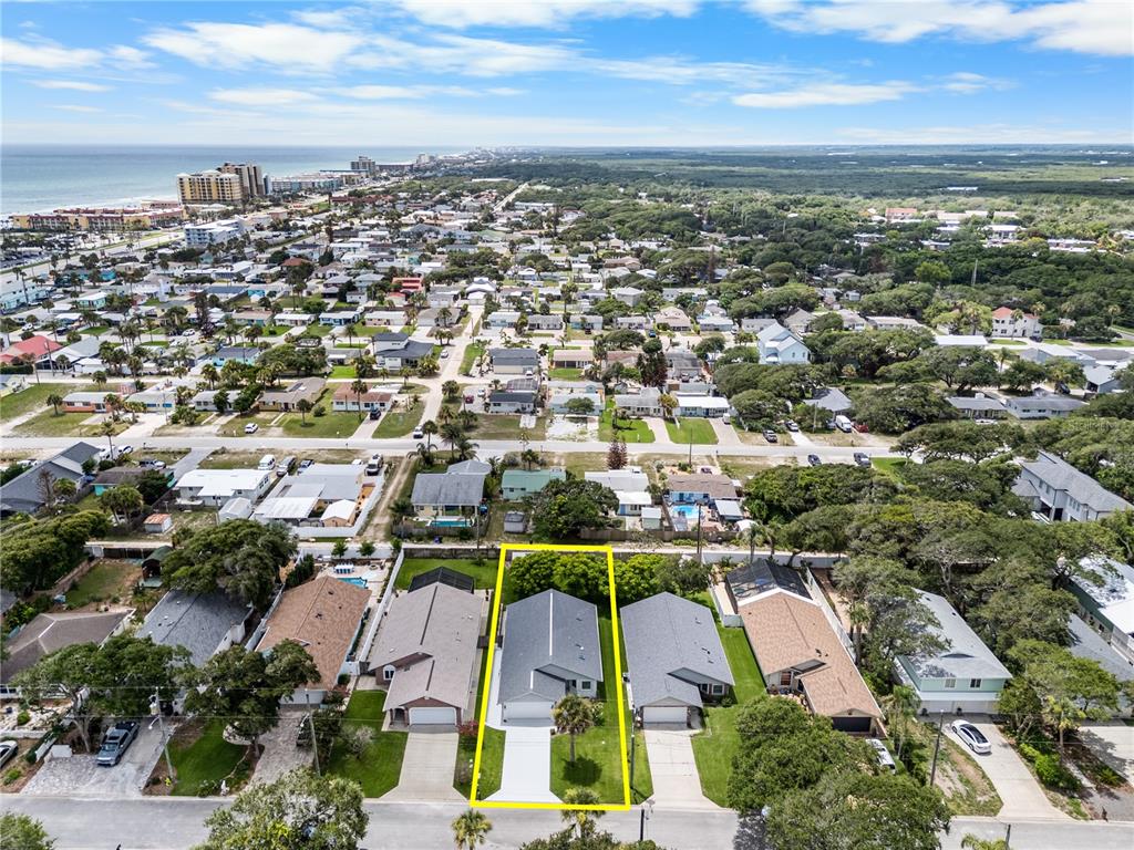 An aerial view shows a single-story house highlighted in yellow within a residential coastal neighborhood — 815 E 23RD AVENUE, NEW SMYRNA BEACH, FL