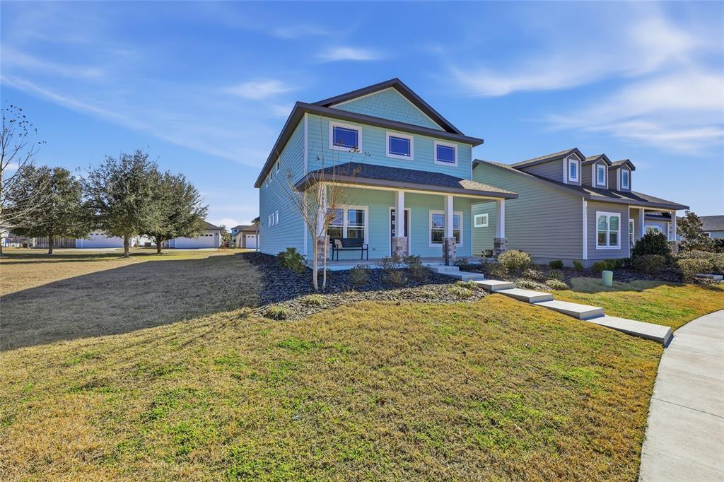 A light blue two-story house with a front porch and a large side yard — 9533 SW 66TH LANE, GAINESVILLE, FL