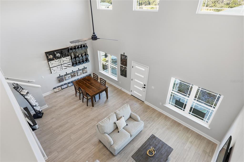 A high-angle view of a living and dining area with light wood floors and high ceilings — 9533 SW 66TH LANE, GAINESVILLE, FL