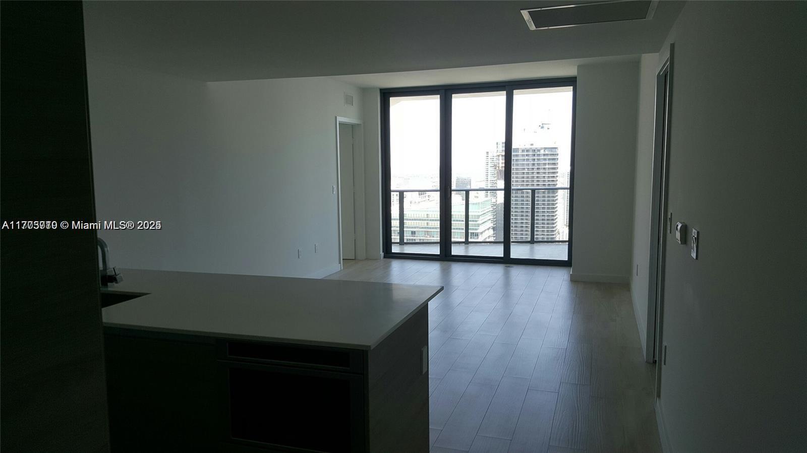 An open-concept living area features light wood flooring, a kitchen island, and floor-to-ceiling windows — 1300 S Miami Ave # 4411, Miami FL 33130, MIAMI, FL