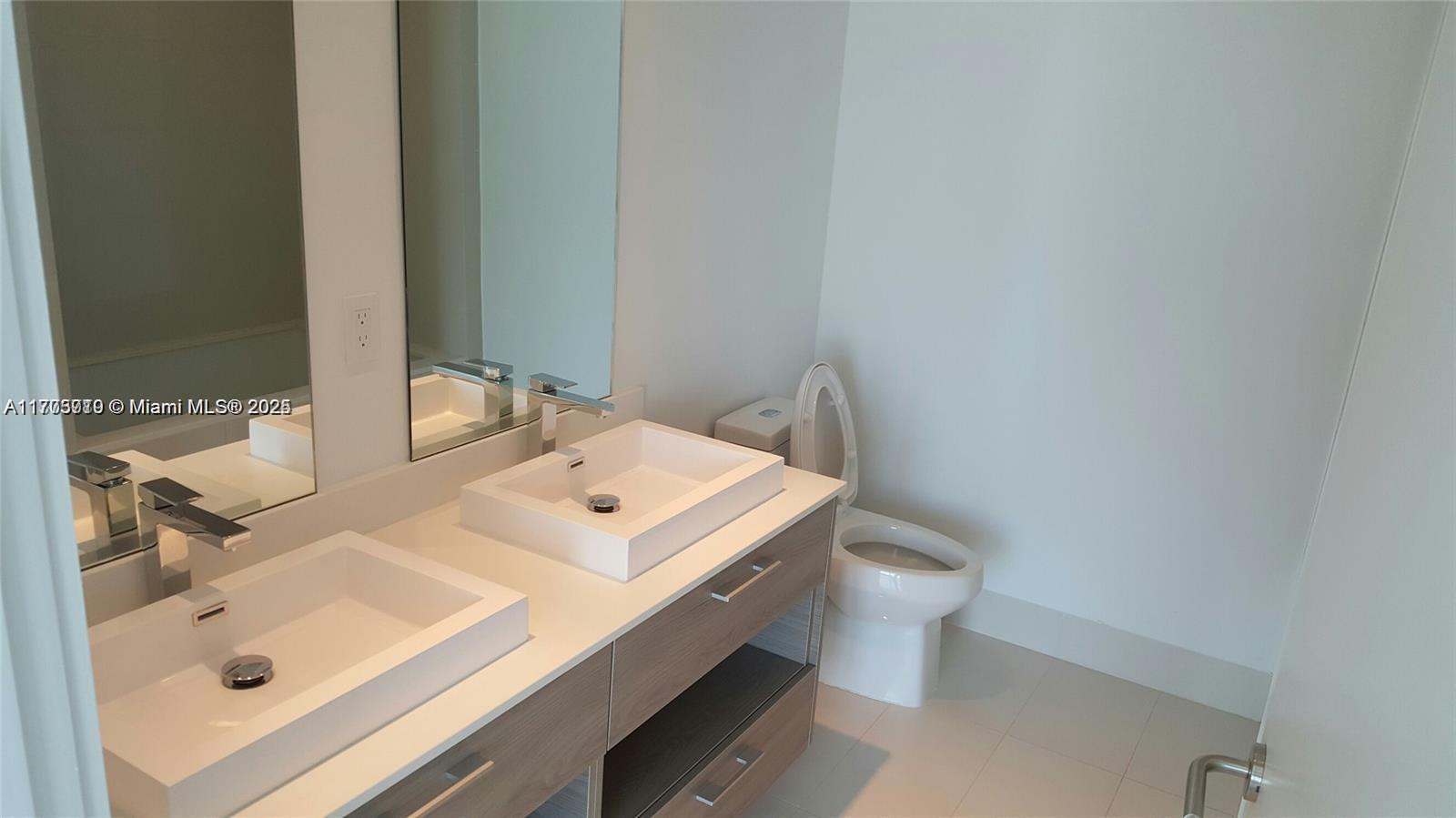 A modern bathroom features a double vanity with vessel sinks and a white toilet — 1300 S Miami Ave # 4411, Miami FL 33130, MIAMI, FL