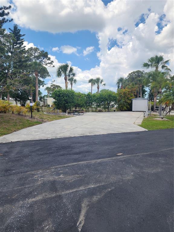 A paved driveway leads to a small storage shed surrounded by palm trees and landscaping — 1674 UNIVERSITY PARKWAY UNIT 328, SARASOTA, FL