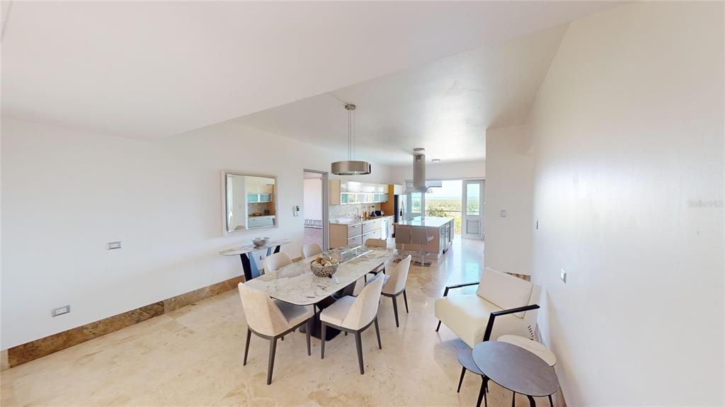A dining area with a marble table and chairs opens into a modern kitchen — 52 LAS VISTAS DE RIO MAR, RIO GRANDE, PR