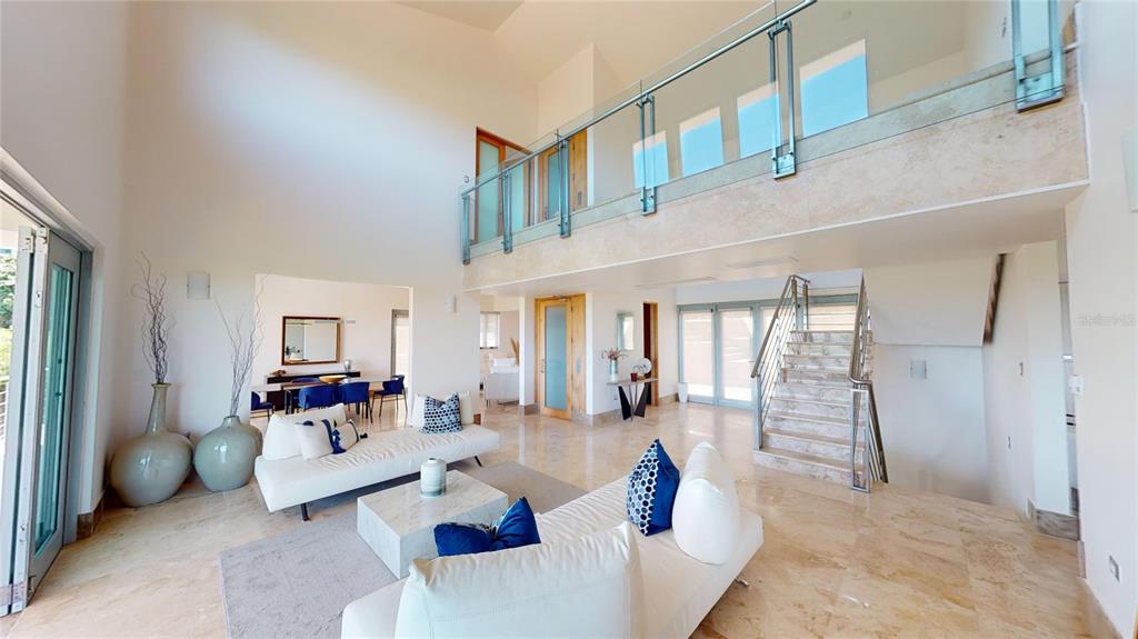 A spacious living room features marble floors, a glass-railed mezzanine, and a central staircase — 52 LAS VISTAS DE RIO MAR, RIO GRANDE, PR