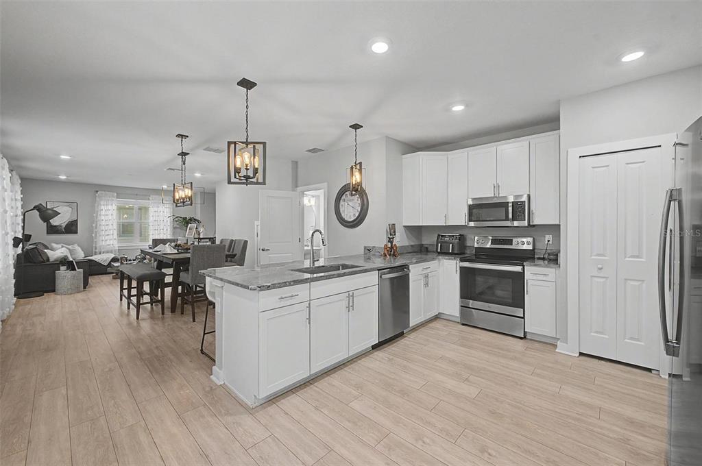 A kitchen with white cabinets, granite countertops, and stainless steel appliances opens to a dining area — 6023 INTERBAY BOULEVARD UNIT 1, TAMPA, FL