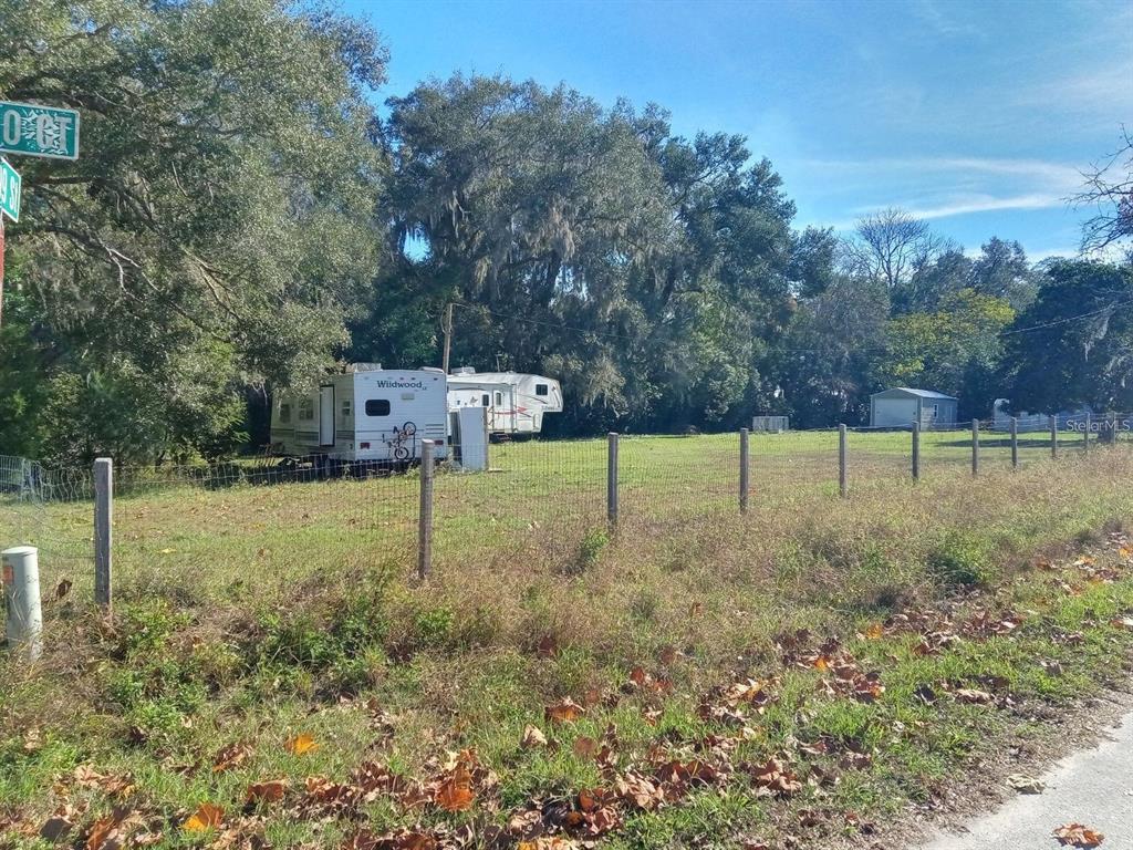 A fenced grassy lot features two parked travel trailers and a small shed — 9895 NE 30TH COURT, ANTHONY, FL