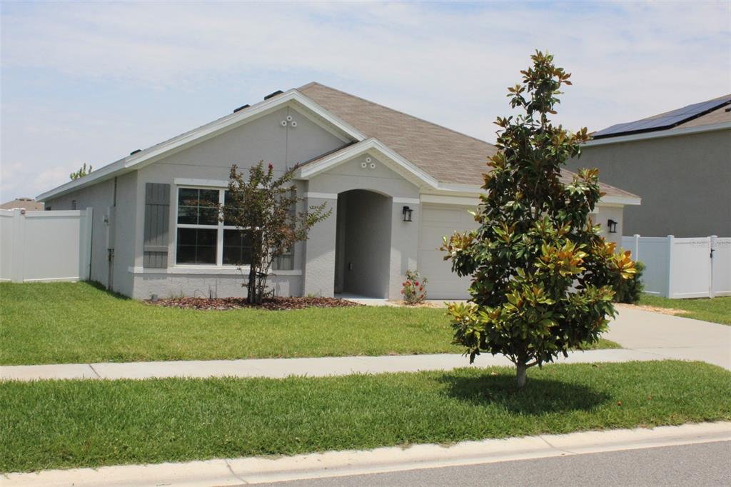 A single-story gray house with a brown roof, a front lawn, and a magnolia tree — 810 WILL SCARLETT AVENUE, RUSKIN, FL