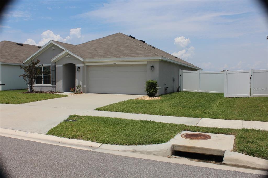 A single-story suburban house with a gray exterior, a two-car garage, and a white fence — 810 WILL SCARLETT AVENUE, RUSKIN, FL