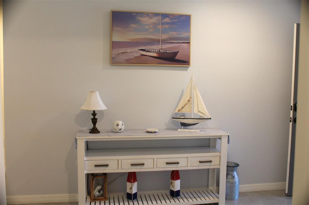 A white console table sits against a light wall beneath a framed sailboat picture — 810 WILL SCARLETT AVENUE, RUSKIN, FL