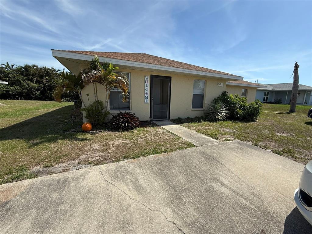 A single-story house with a beige stucco exterior, a concrete driveway, and a palm tree — 11081 PENDLETON AVENUE UNIT A, ENGLEWOOD, FL