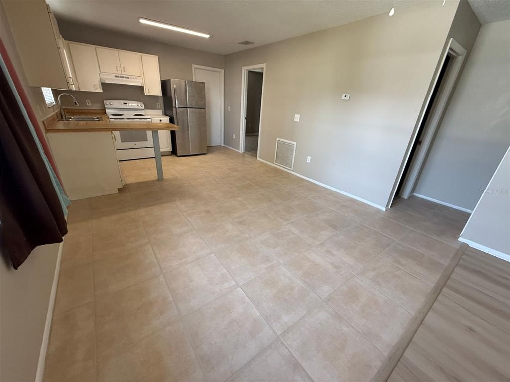A kitchen with white cabinets, stainless steel appliances, and tan tile flooring — 11081 PENDLETON AVENUE UNIT A, ENGLEWOOD, FL