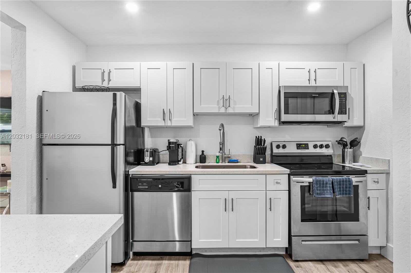 A kitchen features white cabinets, stainless steel appliances, and light-colored countertops — 1521 NE 118th Ter # 1, Miami FL 33161, MIAMI, FL