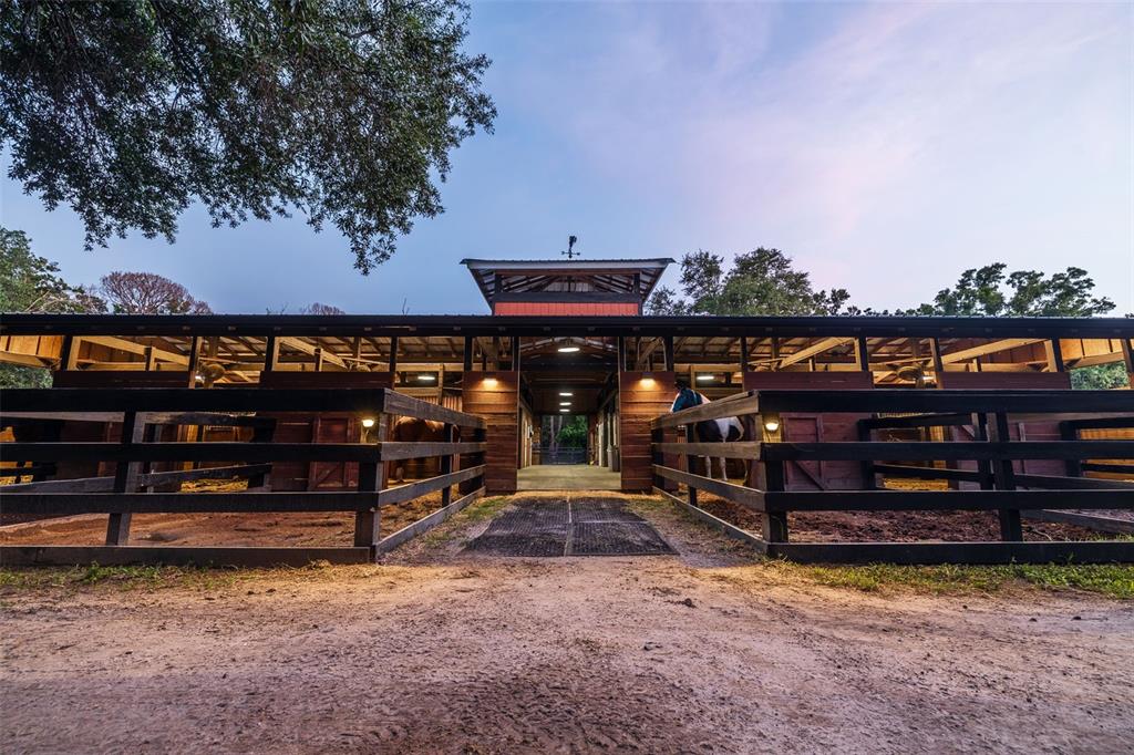 A wooden horse stable with multiple stalls and a central aisle under a clear sky — 8701 64TH STREET N, PINELLAS PARK, FL