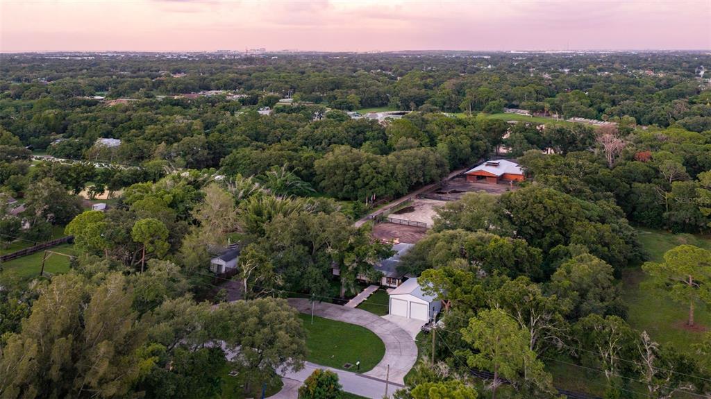 An aerial view shows a house with a detached garage, a riding arena, and surrounding trees — 8701 64TH STREET N, PINELLAS PARK, FL