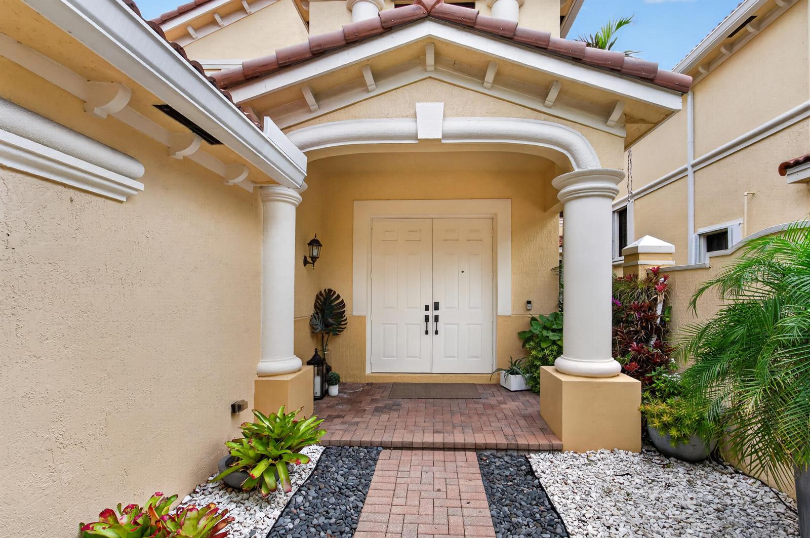 A covered entryway features a brick walkway, white double doors, and two large decorative columns — 1687 Passion Vine Circle # 1687, Weston FL 33326, WESTON, FL