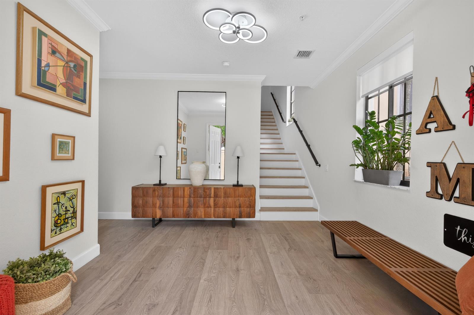 A bright entryway features wood flooring, a wooden console table, a staircase, and wall art — 1687 Passion Vine Circle # 1687, Weston FL 33326, WESTON, FL