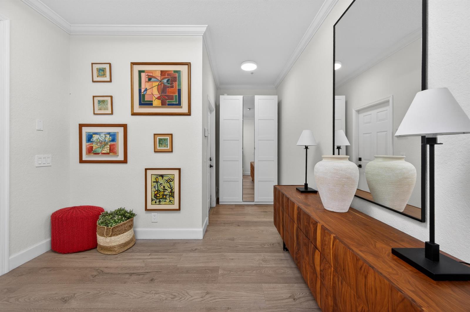 A hallway features a wooden console table, a large mirror, and a gallery wall of art — 1687 Passion Vine Circle # 1687, Weston FL 33326, WESTON, FL