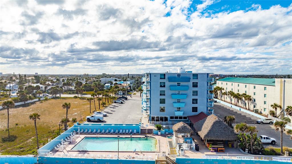 An aerial view shows a multi-story blue hotel building with an outdoor pool and tiki bar — 313 S ATLANTIC AVENUE UNIT 2260, DAYTONA BEACH, FL