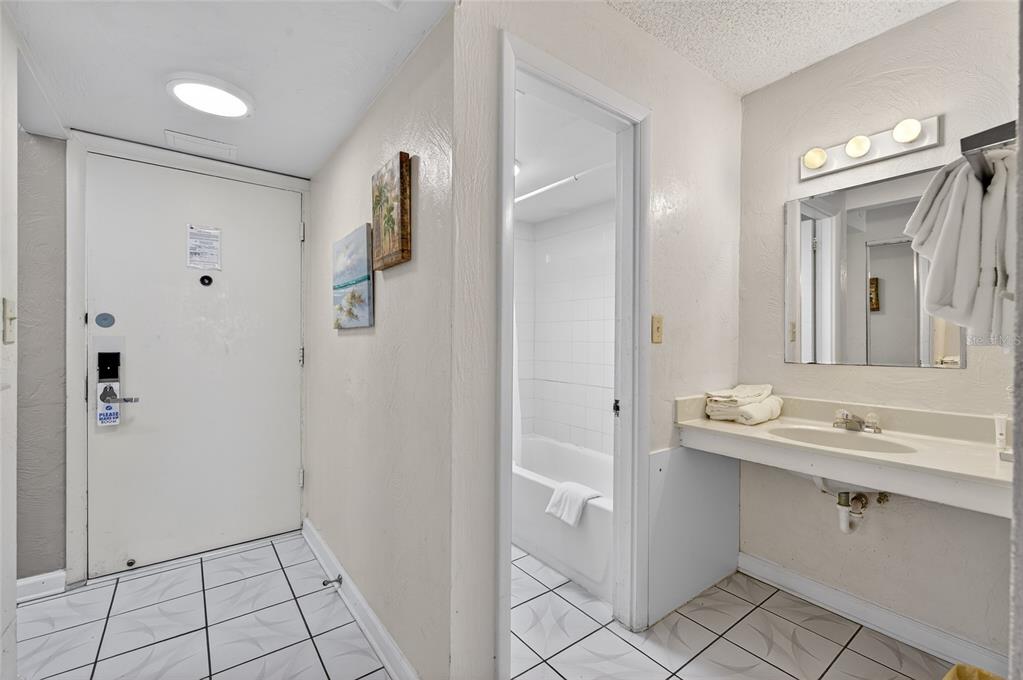 A hotel-style bathroom features a vanity with a sink, a tiled floor, and a tub — 313 S ATLANTIC AVENUE UNIT 2260, DAYTONA BEACH, FL