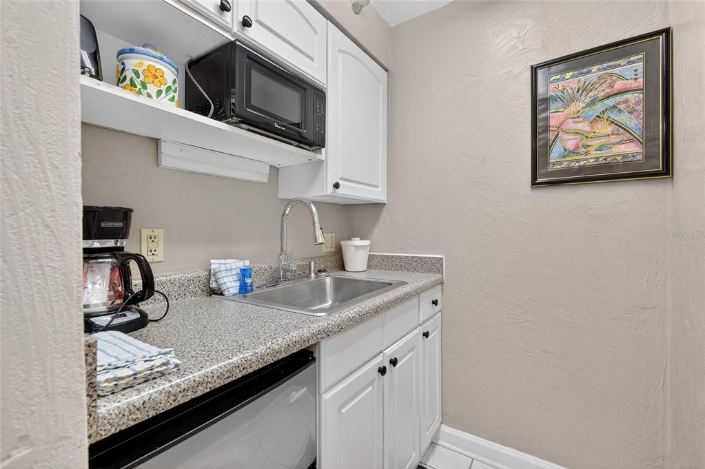 A small kitchenette features white cabinets, a stainless steel sink, and a microwave — 313 S ATLANTIC AVENUE UNIT 2260, DAYTONA BEACH, FL