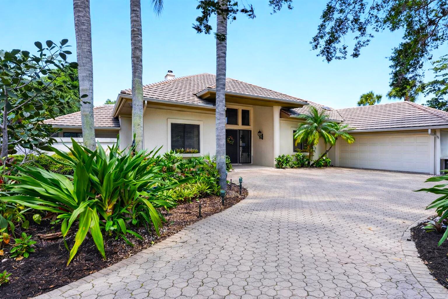A single-story house with a paved driveway, palm trees, and a two-car garage — 6460 SE Winged Foot Drive, Stuart FL 34997, STUART, FL