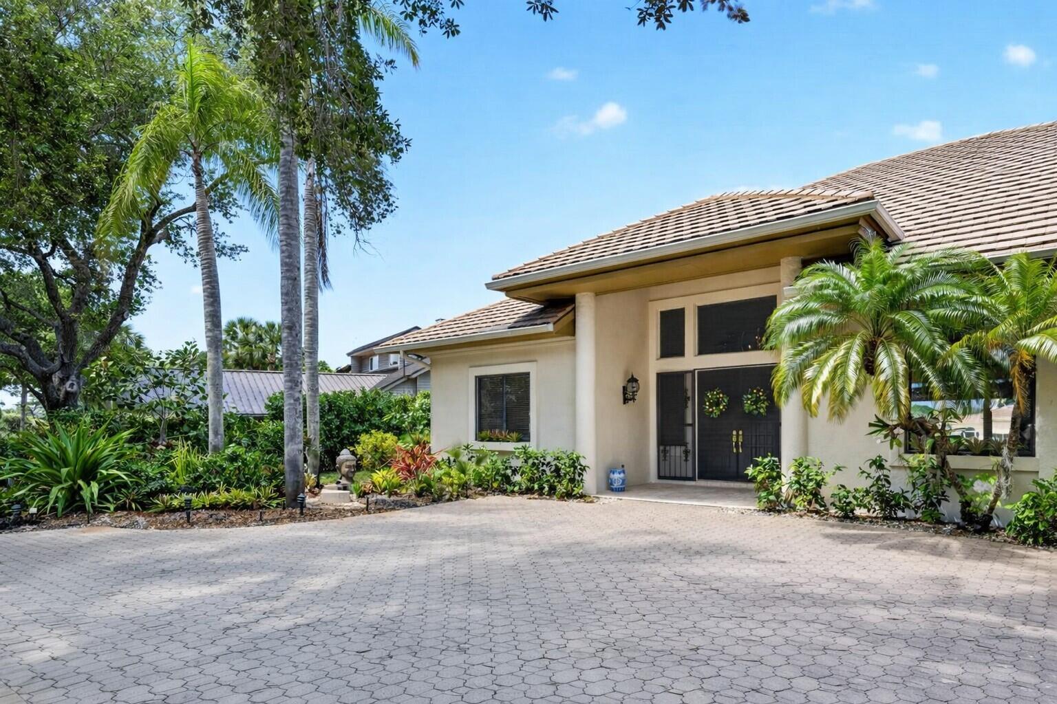 A paved driveway leads to the front entrance of a house with a tiled roof — 6460 SE Winged Foot Drive, Stuart FL 34997, STUART, FL