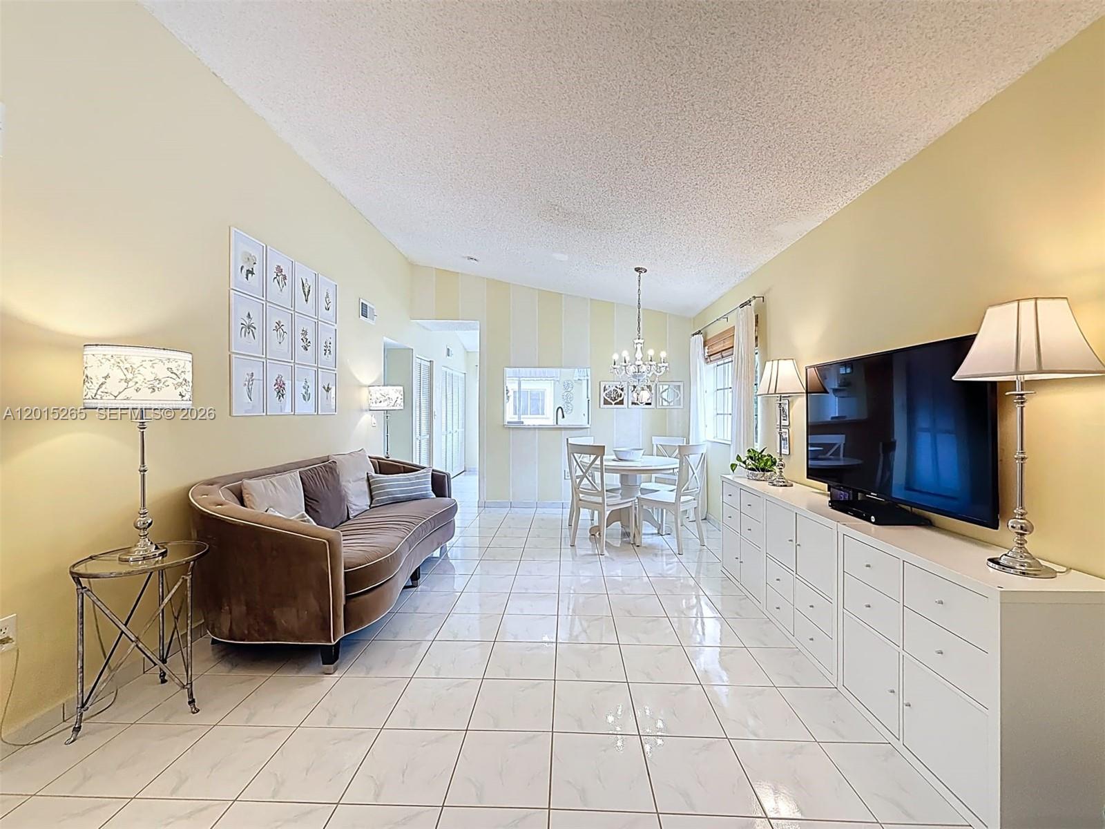 A living and dining area features white tile floors, a brown sofa, and white cabinetry — 6466 SW 130th Pl # 902, Miami FL 33183, MIAMI, FL
