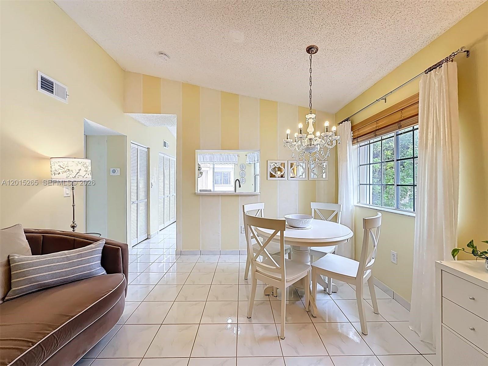 A dining area features a white table, four chairs, a chandelier, and striped yellow walls — 6466 SW 130th Pl # 902, Miami FL 33183, MIAMI, FL