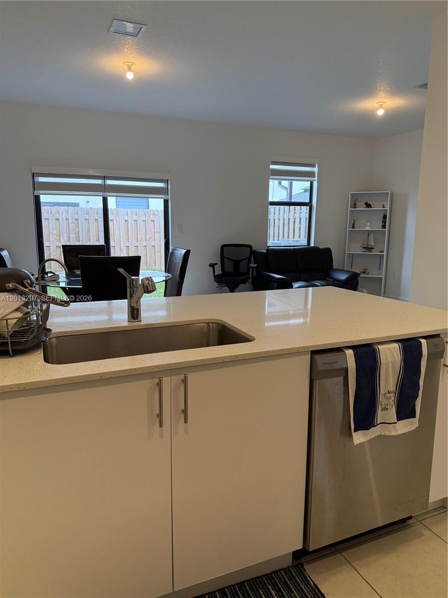 A kitchen island with a stainless steel sink faces a dining and living area — 12955 SW 231st Ter # 12955, Miami FL 33170, MIAMI, FL