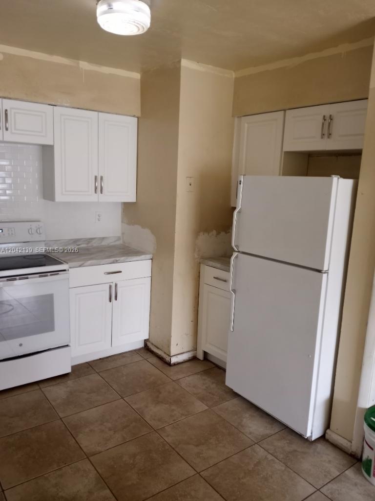 A kitchen features white cabinets, a white refrigerator, a white stove, and tiled flooring — 2901 NW 50th St, Miami FL 33142, MIAMI, FL