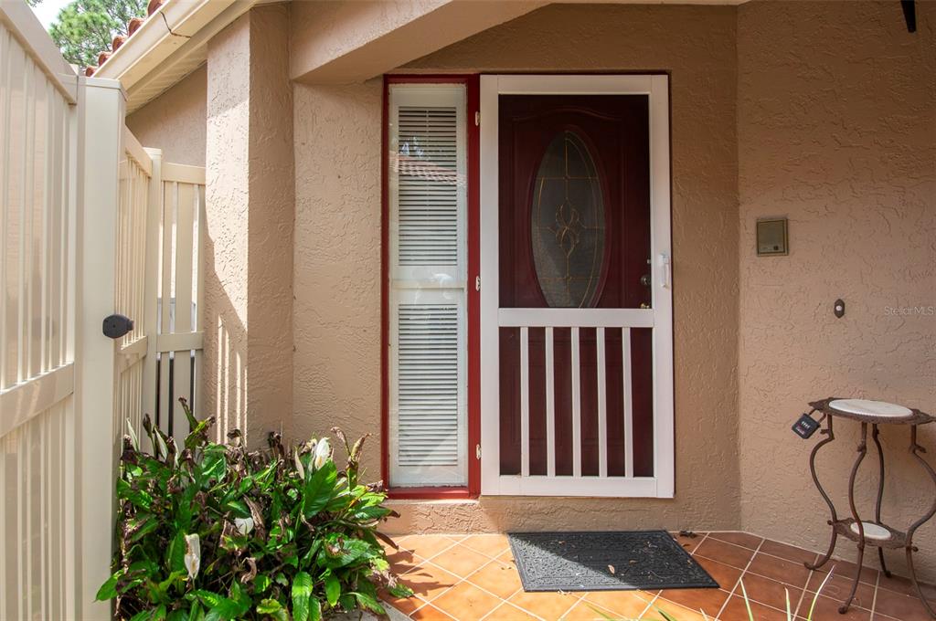 A front entryway features a white screen door with a sidelight and tiled flooring — 491 ST TROPEZ CIRCLE NE, ST PETERSBURG, FL