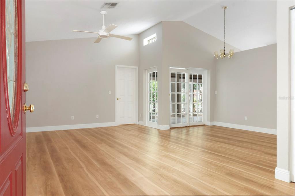 An empty room with light wood floors, a vaulted ceiling, and white French doors — 491 ST TROPEZ CIRCLE NE, ST PETERSBURG, FL