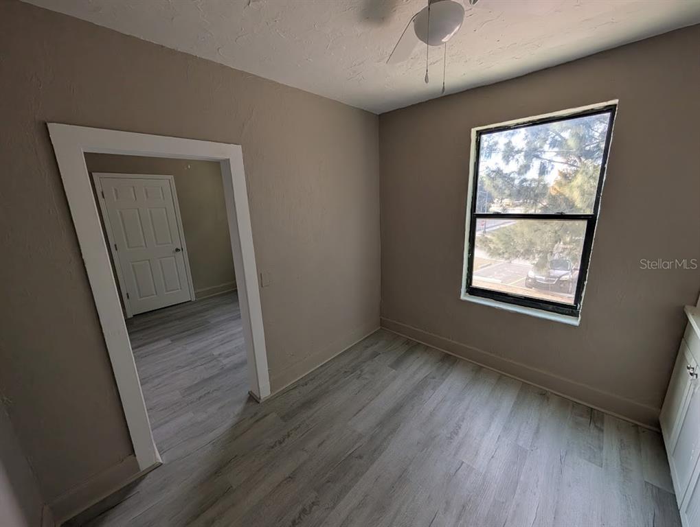 A small room with light wood-look flooring, beige walls, a window, and a doorway — 401 COLONIA LANE E UNIT 8, NOKOMIS, FL