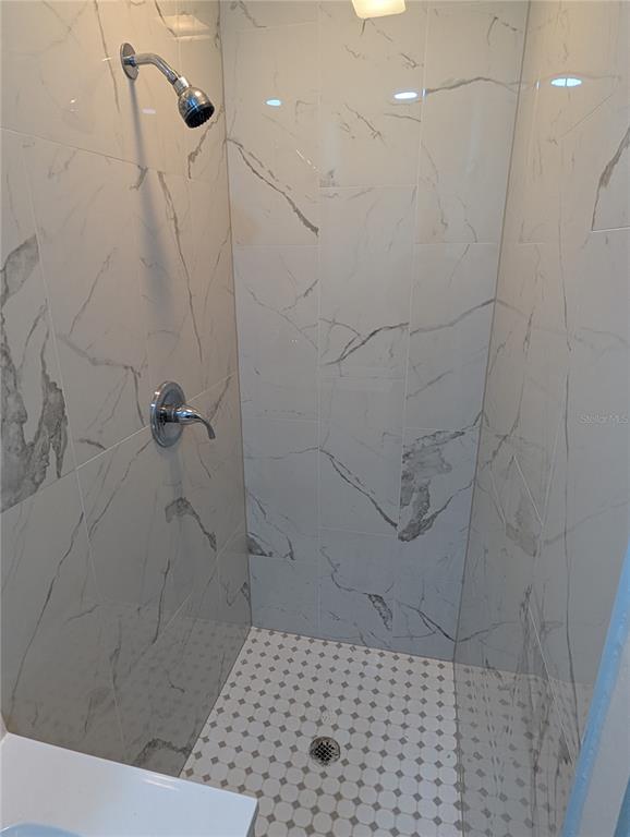 A walk-in shower features white marble-look wall tiles and a small-patterned mosaic tile floor — 401 COLONIA LANE E UNIT 8, NOKOMIS, FL