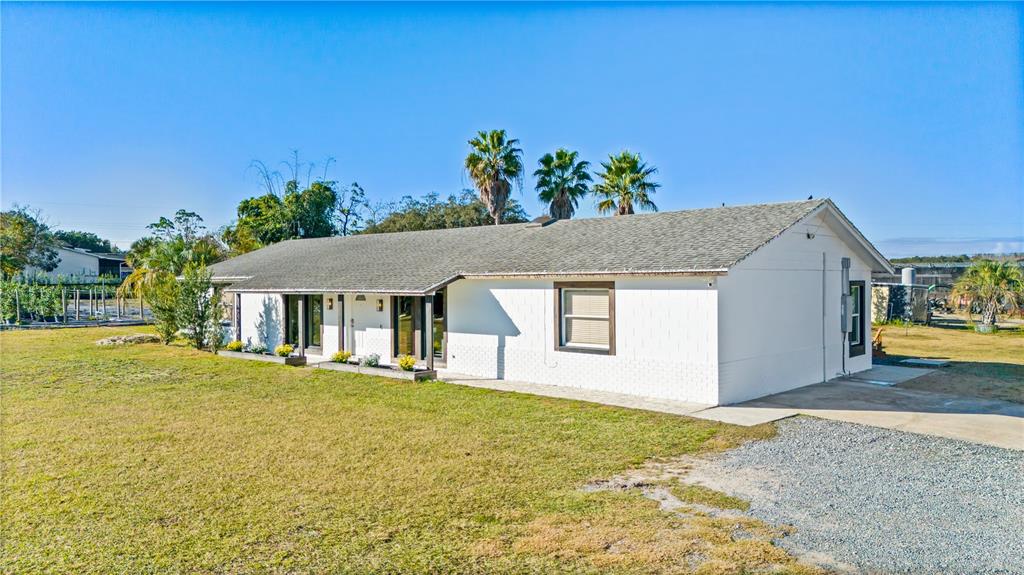 A white, single-story house with a shingled roof sits on a large, grassy lot — 4004 REX DRIVE, WINTER GARDEN, FL