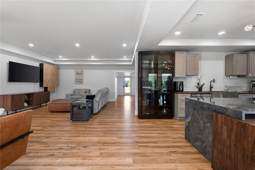 An open-concept living room and kitchen featuring wood-look flooring and a dark stone island — 4004 REX DRIVE, WINTER GARDEN, FL