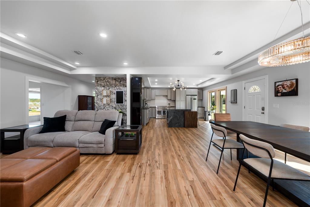An open-concept living and dining area features wood-look flooring, a gray sofa, and kitchen — 4004 REX DRIVE, WINTER GARDEN, FL