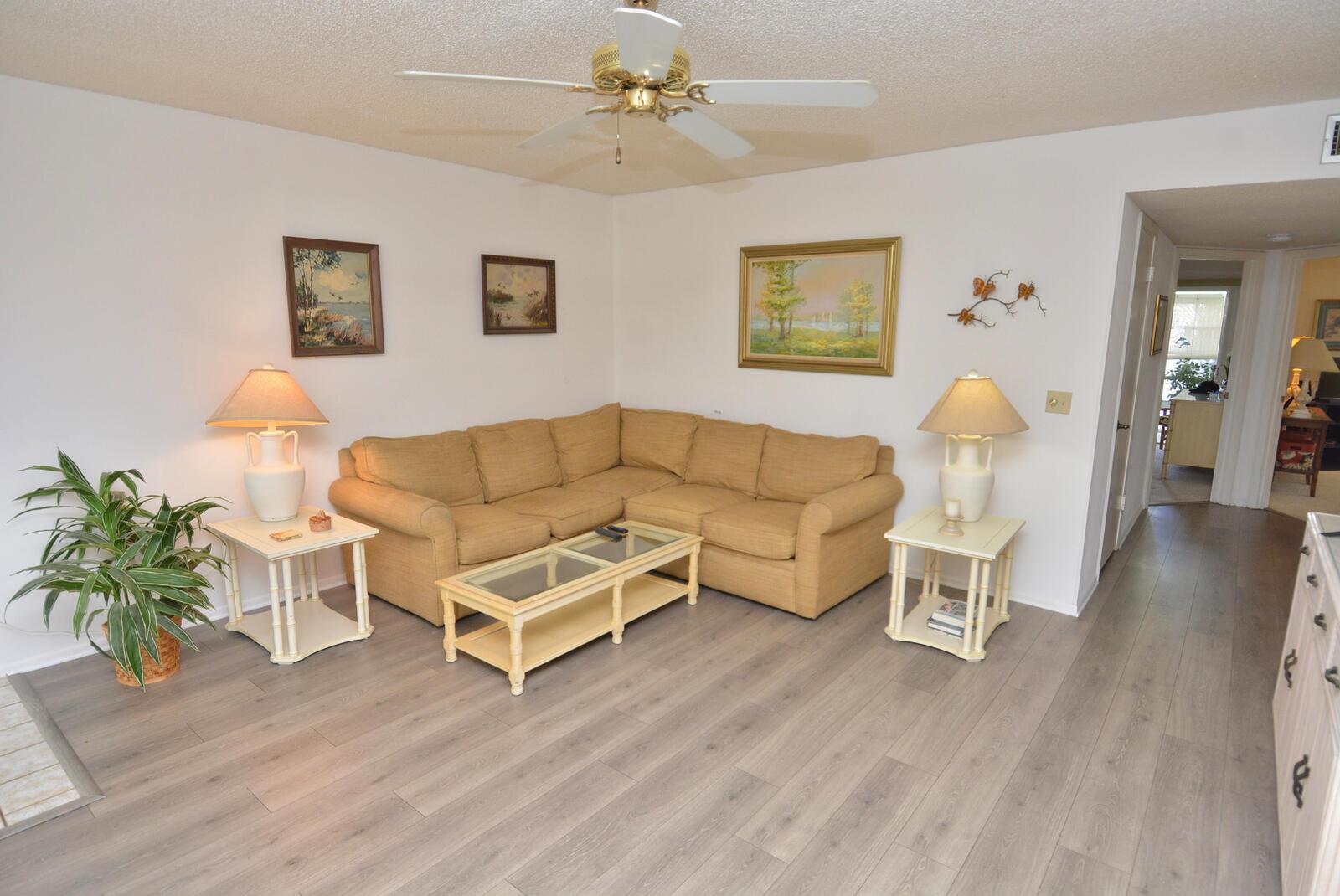 A living room features a tan sectional sofa, glass-top tables, and light wood-look flooring — 1225 NW 21st Street # 3506, Stuart FL 34994, STUART, FL